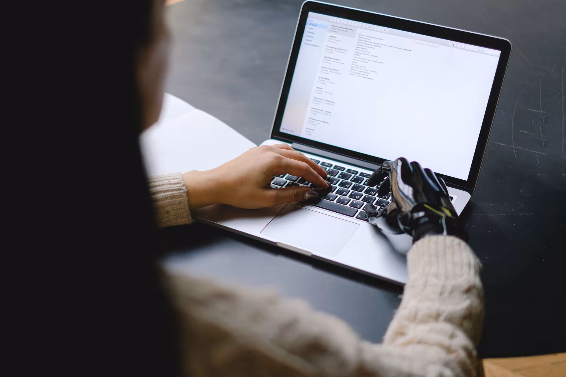 Personne avec une prothèse de main utilisant un ordinateur portable, illustrant l’accessibilité numérique d’un site web